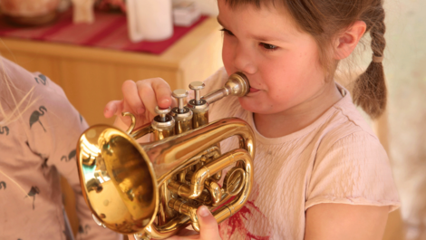 A girl with braids plays the trumpet.