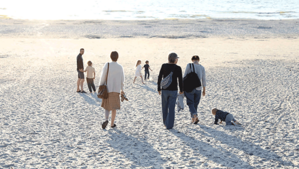 Erwachsene mit Kinder laufen am Strand in Richtung Meer (Foto: PädSek/ Charlotte Fischer)