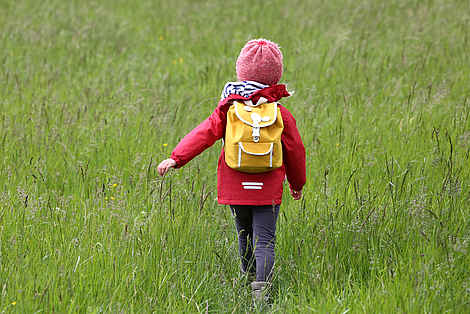 Une fillette traverse une prairie verdoyante